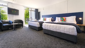 A hotel room with two beds, a TV, a small table, and a sofa. - Urban Lounge Sleepery, SureStay Collection by BW (Rotorua)