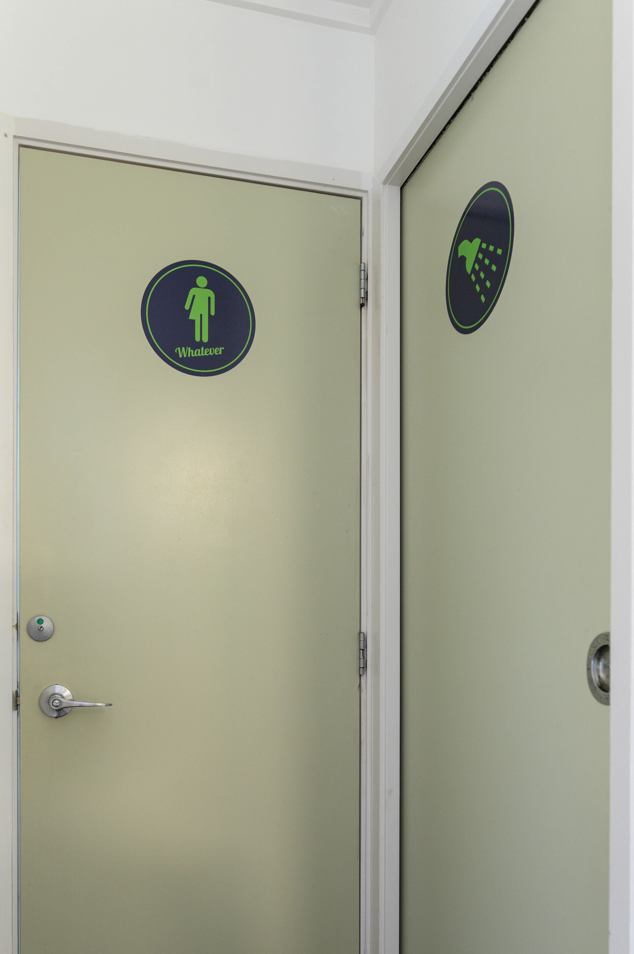 A restroom door with a green sign indicating a men's restroom and a hand symbol for handwashing.