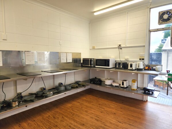 A kitchen with stainless steel countertops, a microwave, a toaster, and a coffee maker.