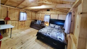 Une chambre dans une cabane en bois, avec un lit, une petite table et un canapé.