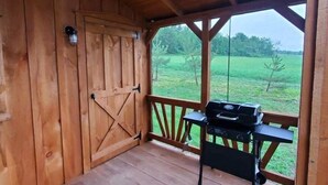 Une terrasse en bois avec un barbecue et une vue sur un champ verdoyant.