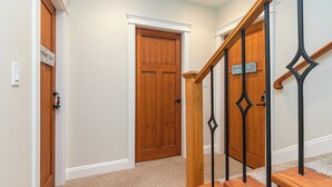 A hallway with a wooden door labeled "Paint Room" and a staircase with a wooden handrail and black balusters. -  2 Bedroom Suite @ Shawnigan Suite Bed and Breakfast (Shawnigan Lake)