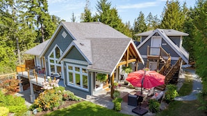 A two-story house with a covered patio, a wooden deck, and a small garden. -  2 Bedroom Suite @ Shawnigan Suite Bed and Breakfast (Shawnigan Lake)
