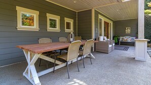 An outdoor patio with a wooden table and wicker chairs, a covered seating area, and a sign reading "LIFE WELCOME".