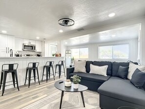 Relax in this stylish living space with a kitchen, sofa, and coffee table.