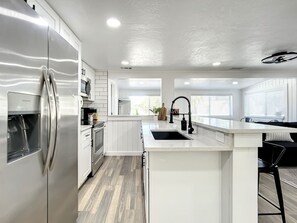 A modern kitchen with a stainless steel refrigerator, a built-in oven, and a sink with a black faucet.