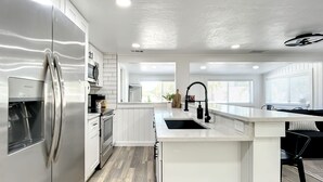 Una cocina moderna con armarios blancos, electrodomésticos de acero inoxidable y una isla central con fregadero.