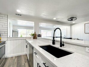 Enjoy cooking in this well-lit kitchen with a large sink, curved faucet, and ample storage.