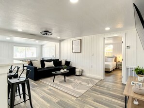 Relax in this stylish living space with a black sofa, coffee table, and dining area.
