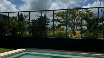 Una piscina rectangular con un cielo azul despejado y nubes al fondo.