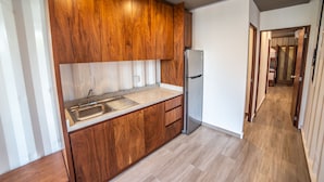 Una cocina moderna con armarios de madera, un lavamanos de acero inoxidable y un refrigerador.