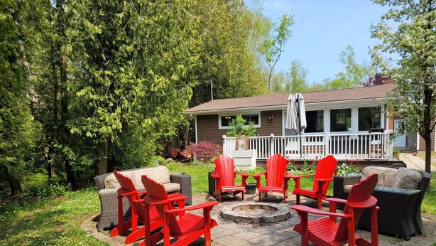 A patio area with red Adirondack chairs, a wicker sofa, and a fire pit.