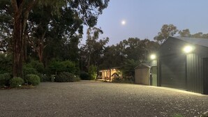 A gravel driveway leading to a building with a covered outdoor area, surrounded by trees and a clear sky. - Don Vally Get Away (Don Valley)