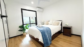Ein Schlafzimmer mit Bett, Fenster, Topfpflanze und Nachttisch.