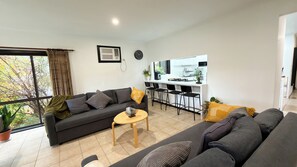 Ein modernes Wohnzimmer mit einer Couch, einem kleinen Tisch und einer Küchenzeile mit Barhocker.
