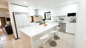 A modern kitchen with white cabinetry, a central island with stools, a built-in stove, and a dishwasher. - Don Vally Get Away (Don Valley)