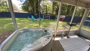 Ein Whirlpool mit Blick auf einen Garten, inklusive einer überdachten Terrasse und Gartenmöbeln.
