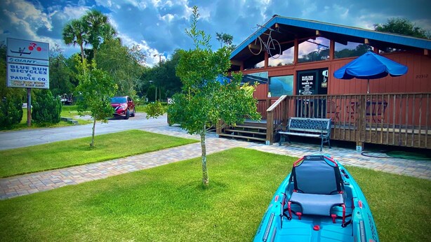 Ein Tretboot in einer grünen Wiese, im Hintergrund ein Gebäude.