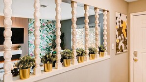 A hallway with a white balustrade, a TV mounted on the wall, and a door with a gold doorknob.