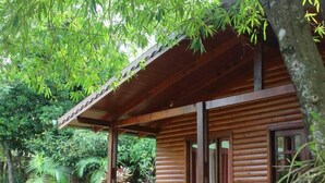 A wooden cabin with a porch, surrounded by lush greenery. - Raices Pampeanas (Puerto Iguazú)