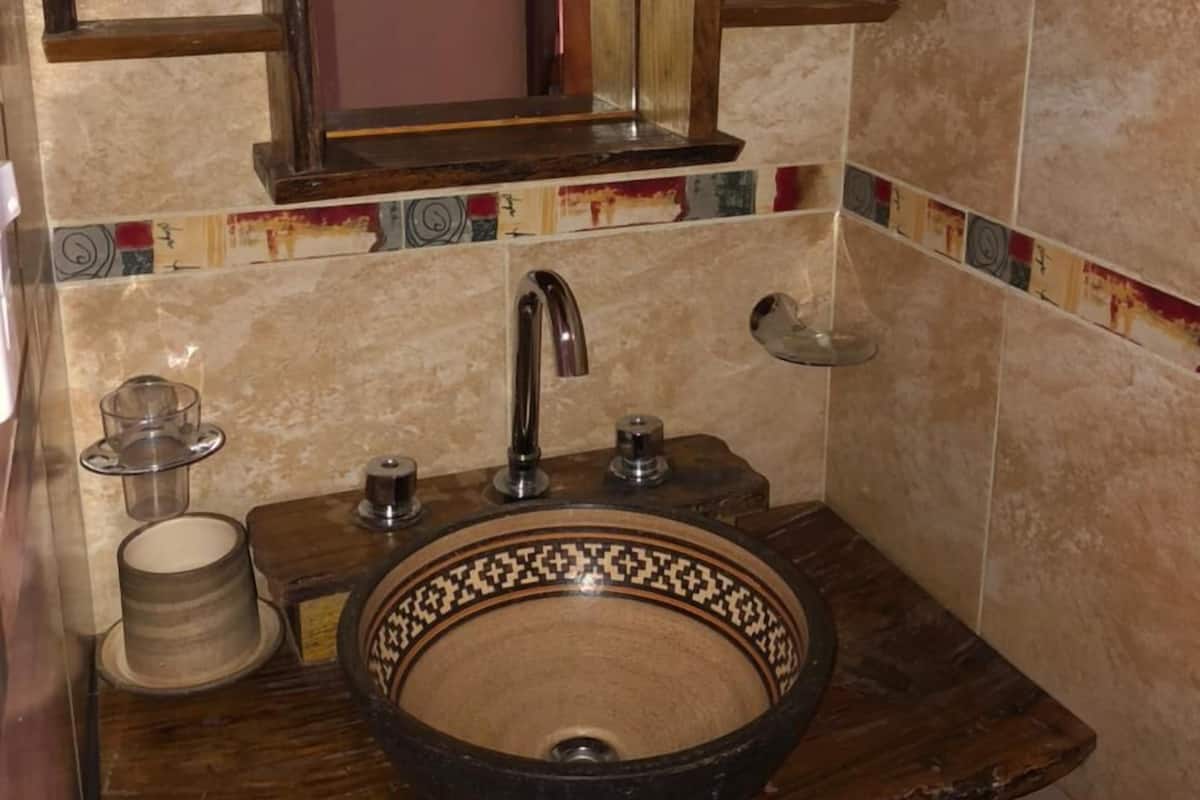 Une salle de bain avec un meuble-lavabo en bois, un grand miroir, un lavabo doté d’une cuve décorative et un porte-serviettes.