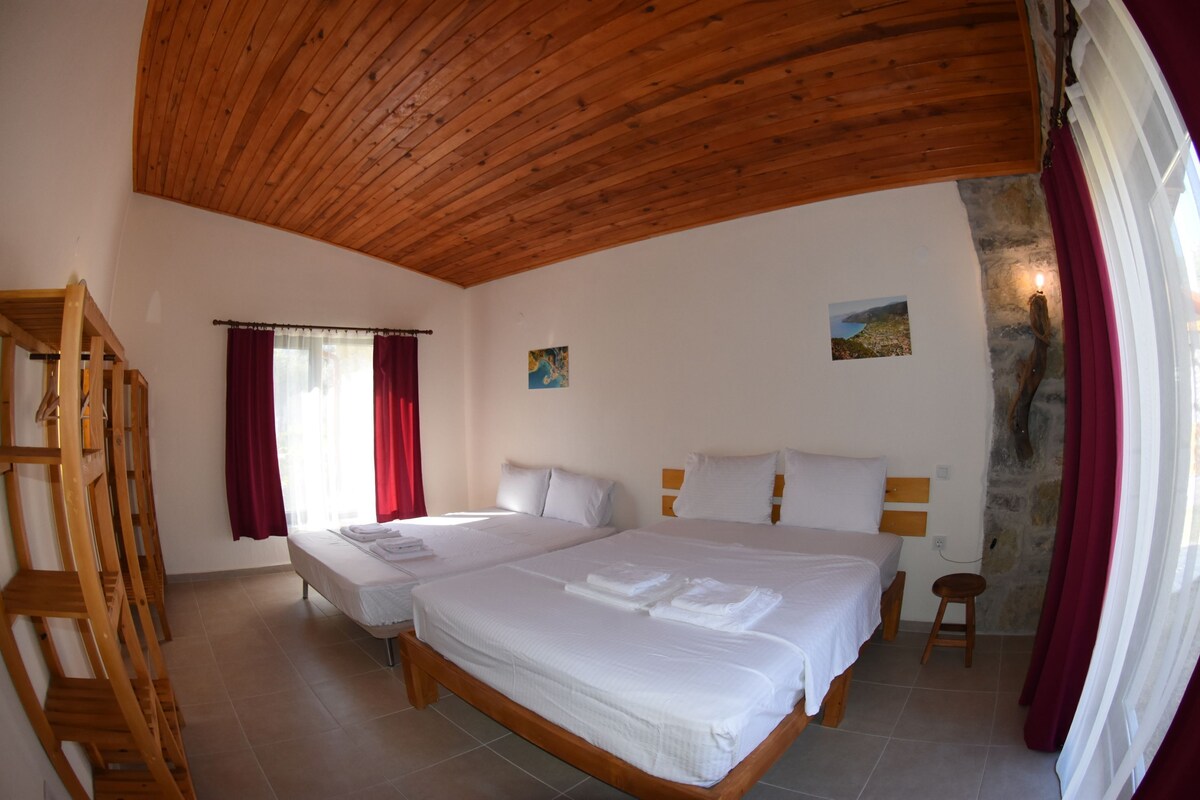 Een slaapkamer met twee bedden, houten plafond en stenen muur.