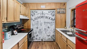 A compact kitchen with wooden cabinets, a red refrigerator, a coffee maker, and a laundry room sign. - Cozy and Private Smoky Mountain escape-perfect for a romantic getaway (Cosby)
