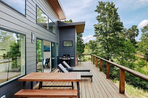 EcoModMtn is a 3BR/3.5BA luxury retreat with panoramic fall views, floor-to-ceiling windows, a gas fireplace, private hot tub, firepit, and designer kitchen. Perfect for families, couples, or friends seeking cozy mountain elegance this autumn.