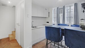 Uma cozinha moderna com armários brancos, pia e área de refeições com cadeiras azuis.