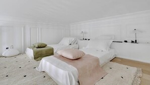 Quarto minimalista com duas camas, uma janela grande e esquema de cores branco.