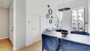 A modern kitchen with a white countertop, blue chairs, and a hanging light fixture. - Maison Labruyère - Aviau Suite (Bordeaux)
