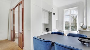 Eine moderne Küche mit weißen Schränken, einer dunklen Arbeitsplatte und blauen Stühlen.