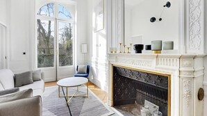 Ein geräumiges Wohnzimmer mit einem weißen Kamin, einem runden Couchtisch und einem blauen Sofa.
