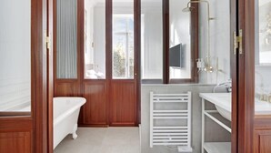 Ein Badezimmer mit einer freistehenden Badewanne, einem weißen Heizkörper und einem Waschtisch mit Spiegel.