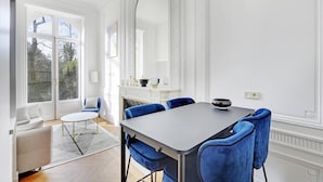 Ein Essbereich mit Tisch und blauen Stühlen, einem Kamin und einem großen Spiegel.