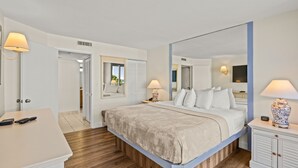 Ein Hotelzimmer mit einem großen Bett, Nachttischen, einem Schreibtisch und einem Spiegel.