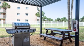 Un espacio al aire libre techado con una parrilla, una mesa de picnic y un extintor.