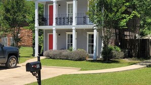 A two-story residential building with a balcony, a mailbox, and a well-maintained lawn. - It's Five O'Clock off South Lamar (Oxford)