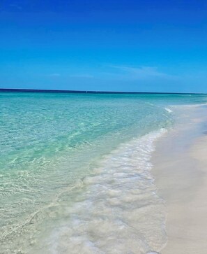A beach with clear turquoise water and a sandy shore.