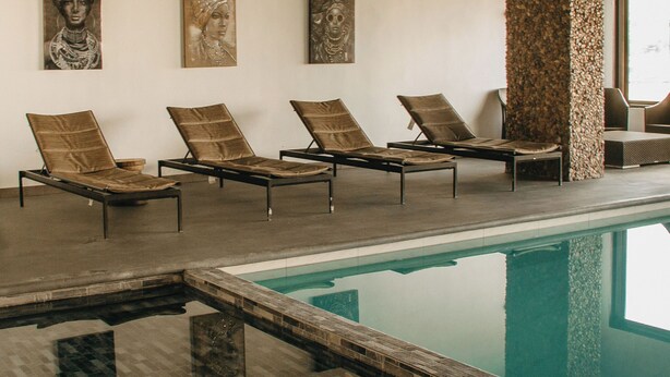 A poolside area with lounge chairs and artwork on the wall. - Hotel María Bonita Chihuahua (Chihuahua)