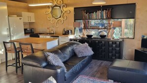 A modern kitchen with a dining area, a sofa, and a television. - Luxury  Container House Auckland Airport (Auckland)