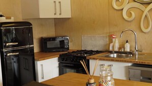 A kitchen with a refrigerator, microwave, stove, and sink. - Luxury  Container House Auckland Airport (Auckland)
