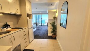 A modern kitchen with white cabinets, a built-in oven, and a large window overlooking a balcony.