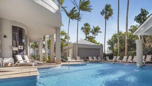 A pool area with lounge chairs and palm trees.