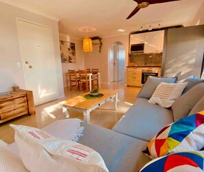 A modern living room with a sofa, a coffee table, and a dining area.