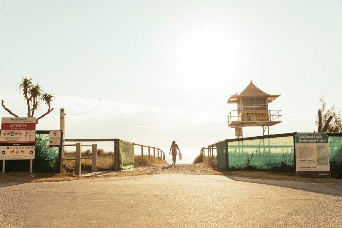 Une tour de surveillance des sauveteurs à l’entrée d’une plage, avec une pancarte indiquant le projet de renforcement du littoral de Gold Coast.