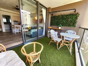 Enjoy a peaceful retreat with a balcony offering a glass door to a kitchen or dining area, a wicker table, and a vertical garden.