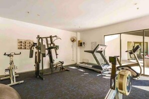 Ein Heimfitnessraum mit Laufband, Crosstrainer und Kraftgeräten.