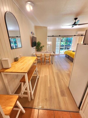 A compact living space with a dining area, a TV mounted on the wall, and a ceiling fan. - [Holiday Apartment] In Ramada Resort- Port Douglas (Port Douglas)