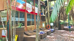 A spa with a red and white sign, outdoor seating, and tropical plants.